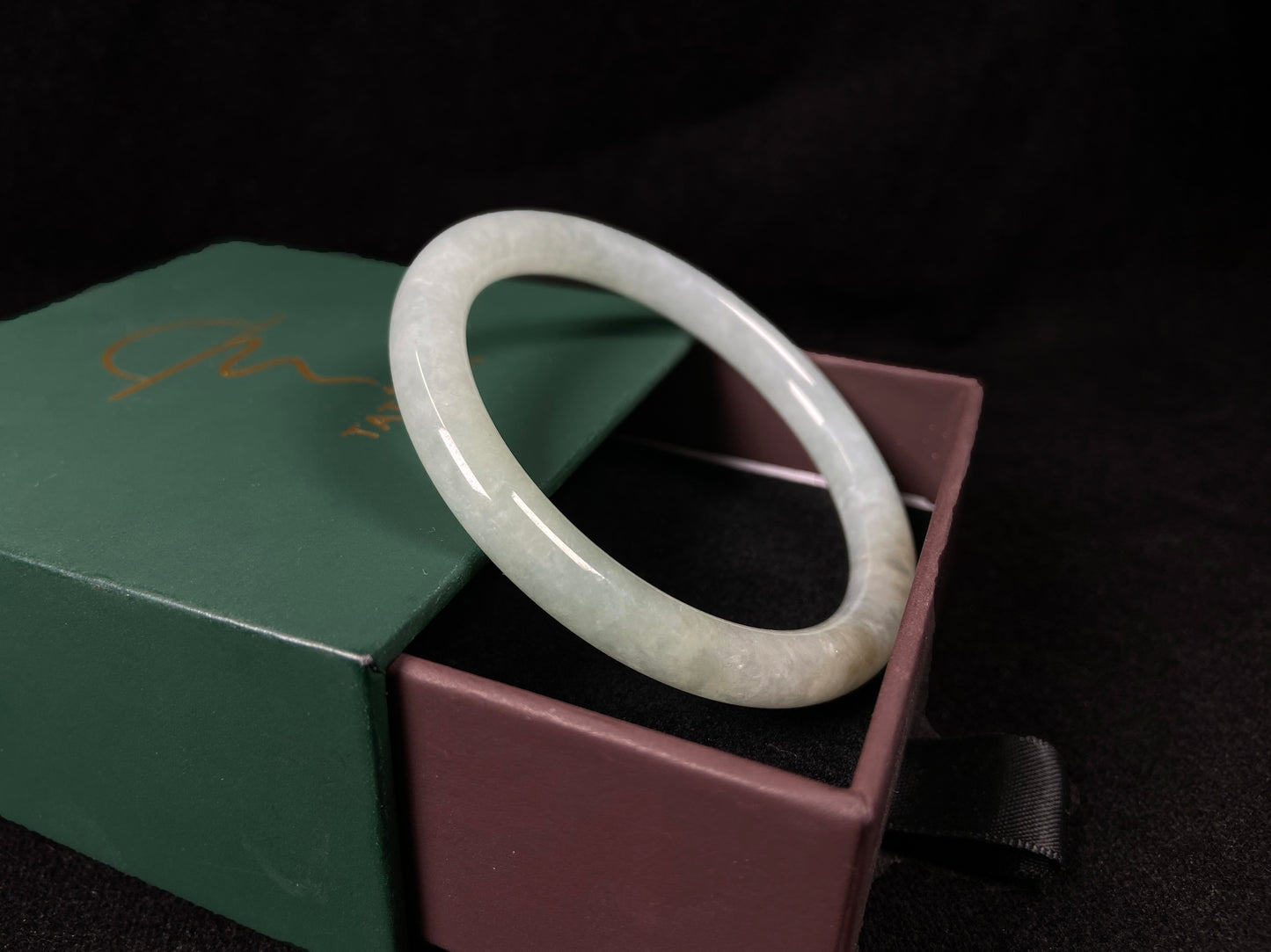This jadeite bangle has a soft pale cyan base with cream undertones and faint gold streaks.
