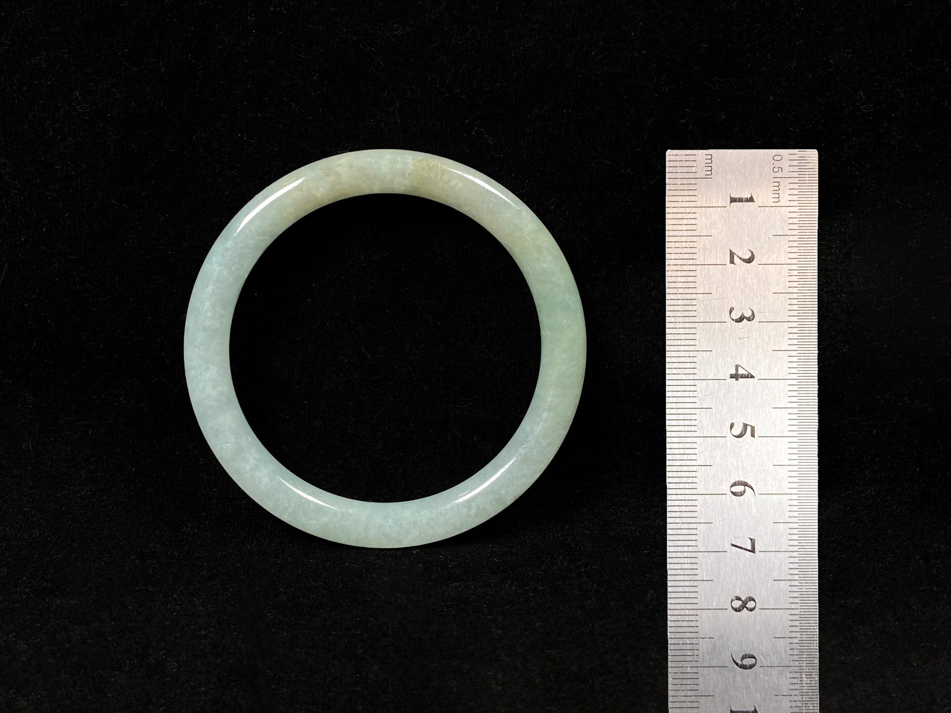 This jadeite bangle has a soft pale cyan base with cream undertones and faint gold streaks.
