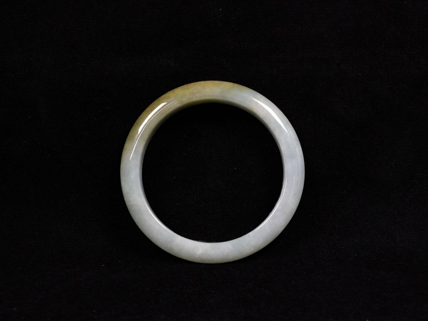 This jadeite bangle features a graceful gradient from fresh green to warm yellow.