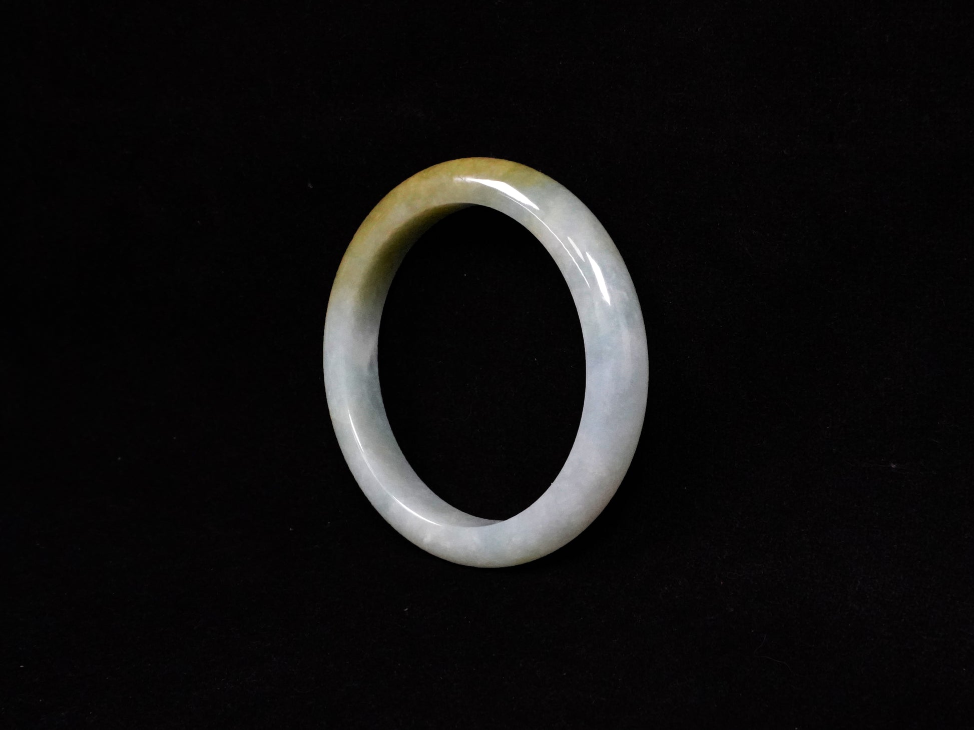 This jadeite bangle features a graceful gradient from fresh green to warm yellow.
