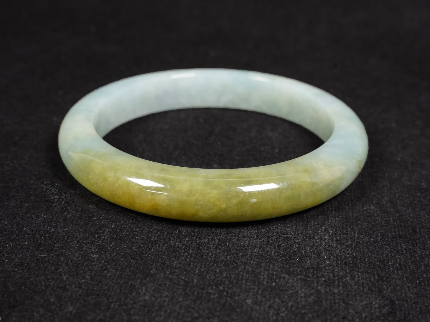 This jadeite bangle features a graceful gradient from fresh green to warm yellow.