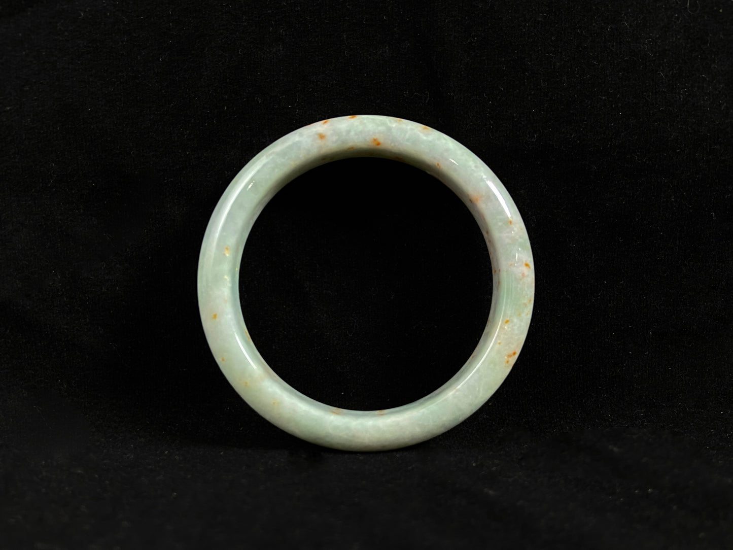 A white and green jade bangle with speckled gold inclusions