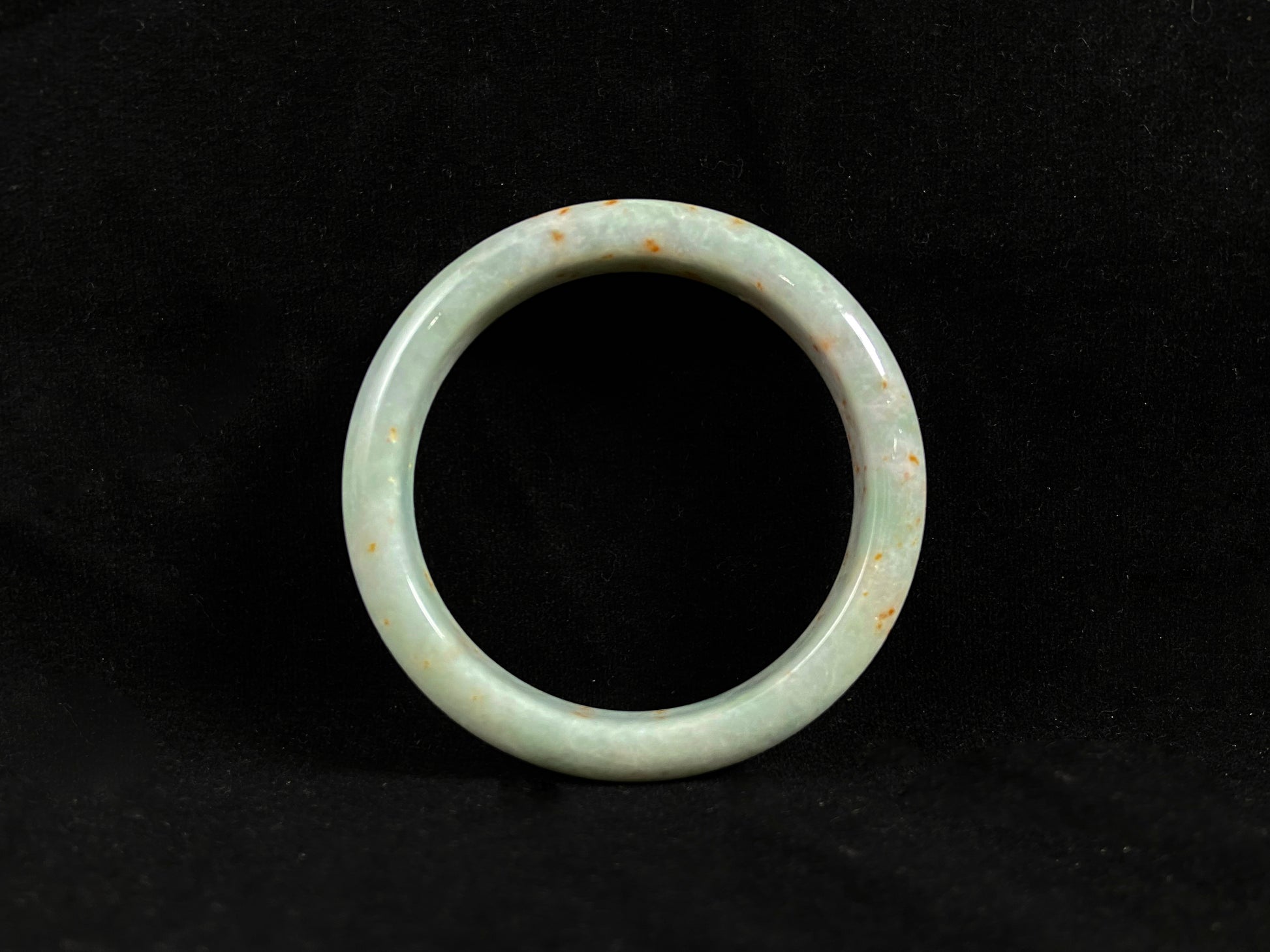 A white and green jade bangle with speckled gold inclusions