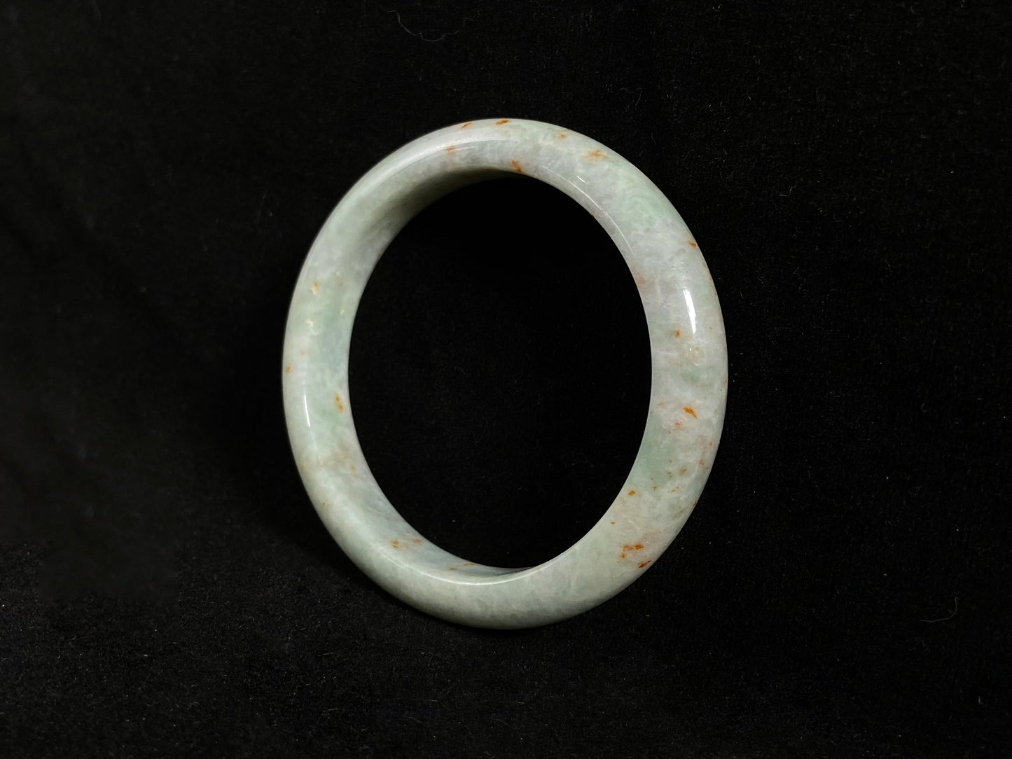 A white and green jade bangle with speckled gold inclusions
