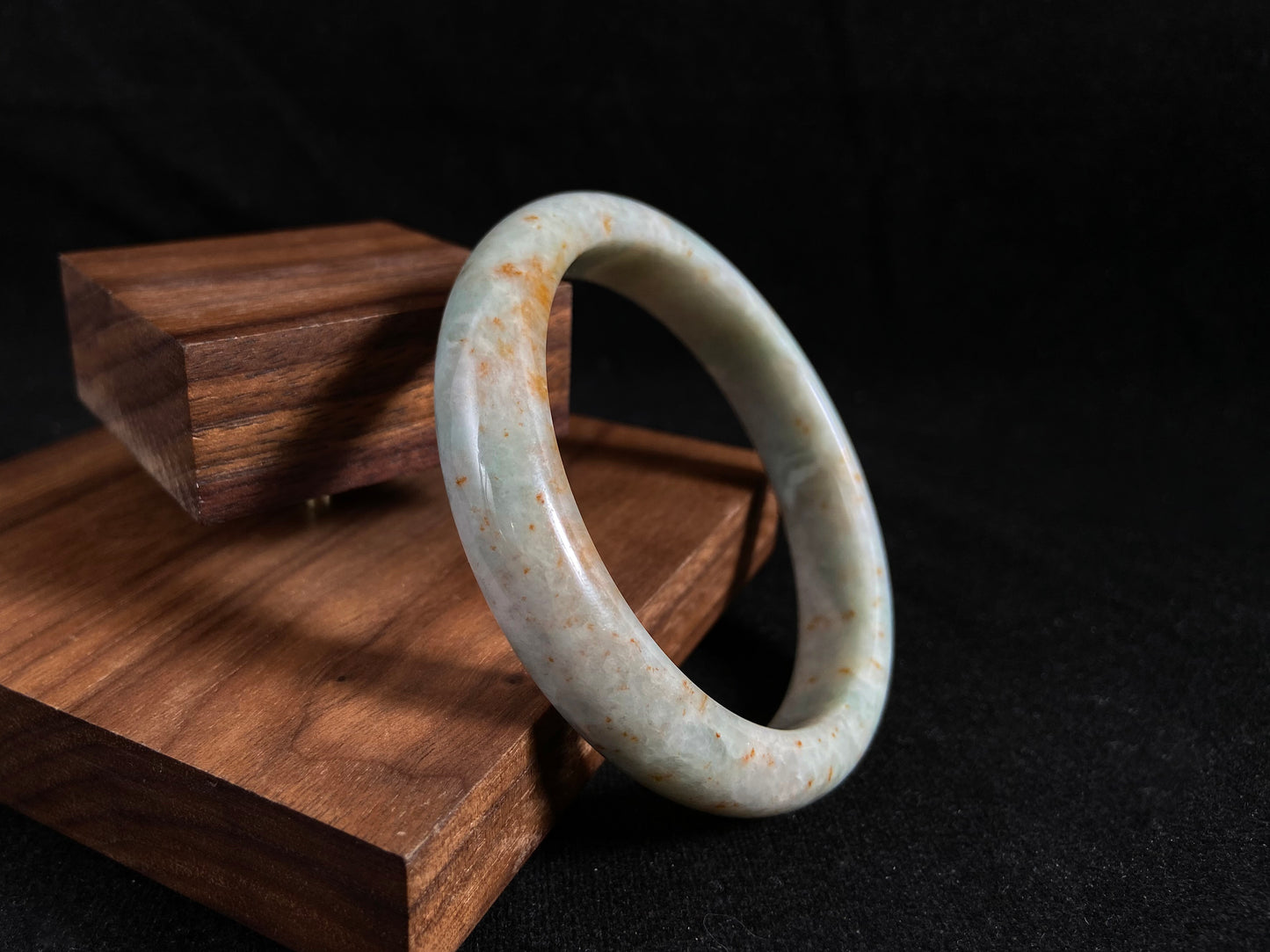 A white and green jade bangle with speckled gold inclusions