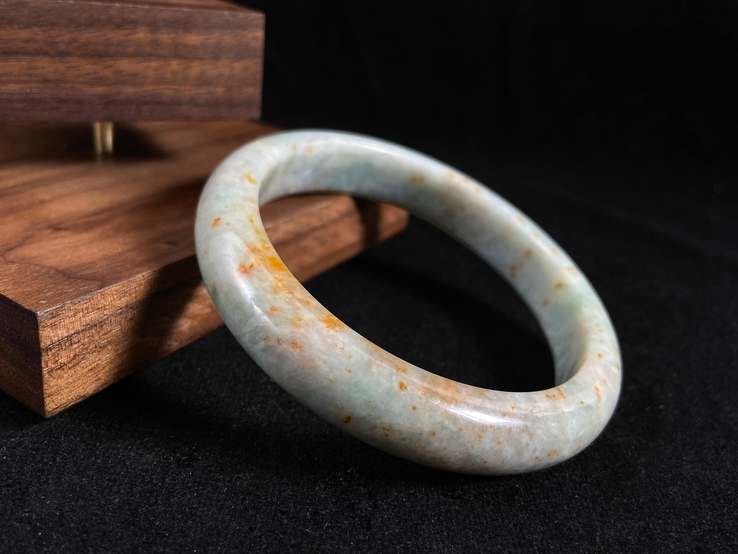 A white and green jade bangle with speckled gold inclusions