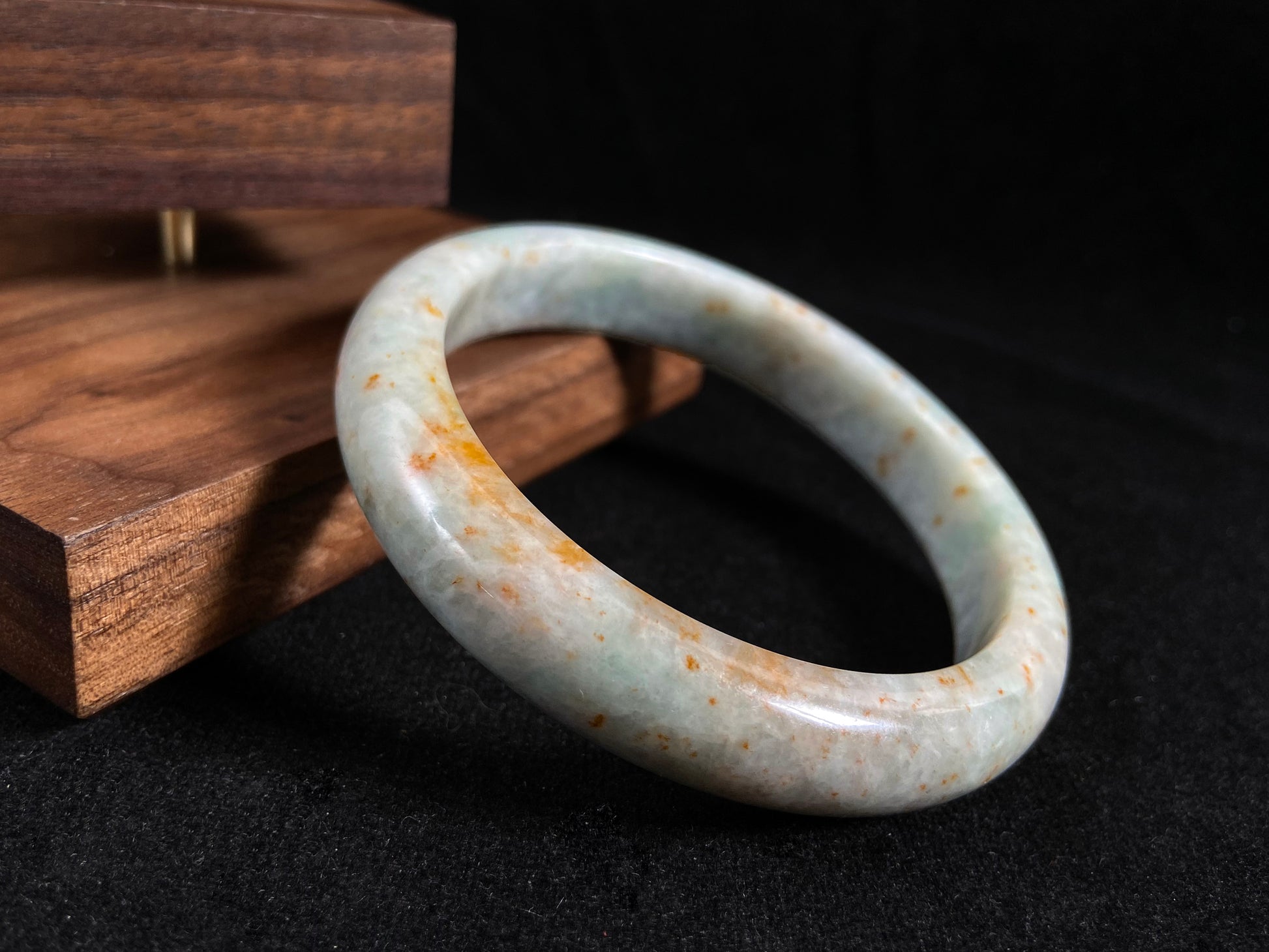 A white and green jade bangle with speckled gold inclusions