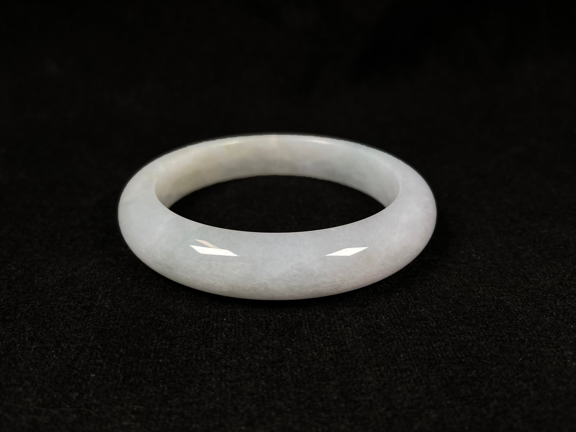 This creamy white jadeite bangle carries soft golden undertones, exuding warmth and elegance.