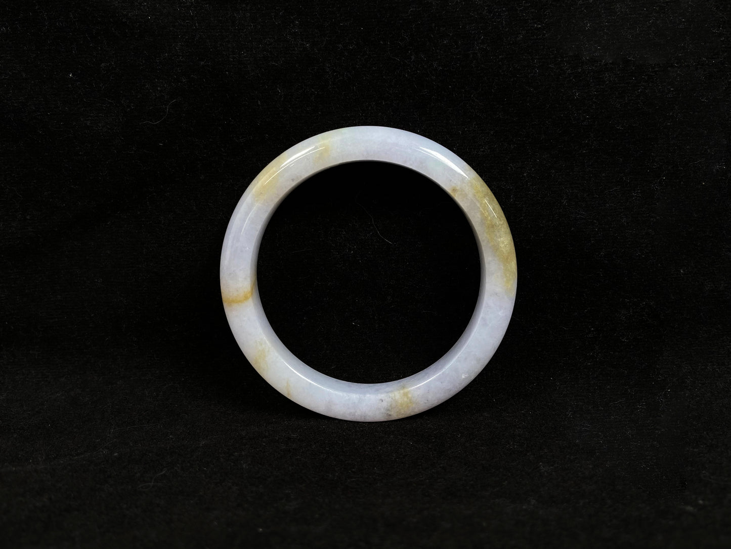 This jadeite bangle features a creamy white base adorned with golden speckles.