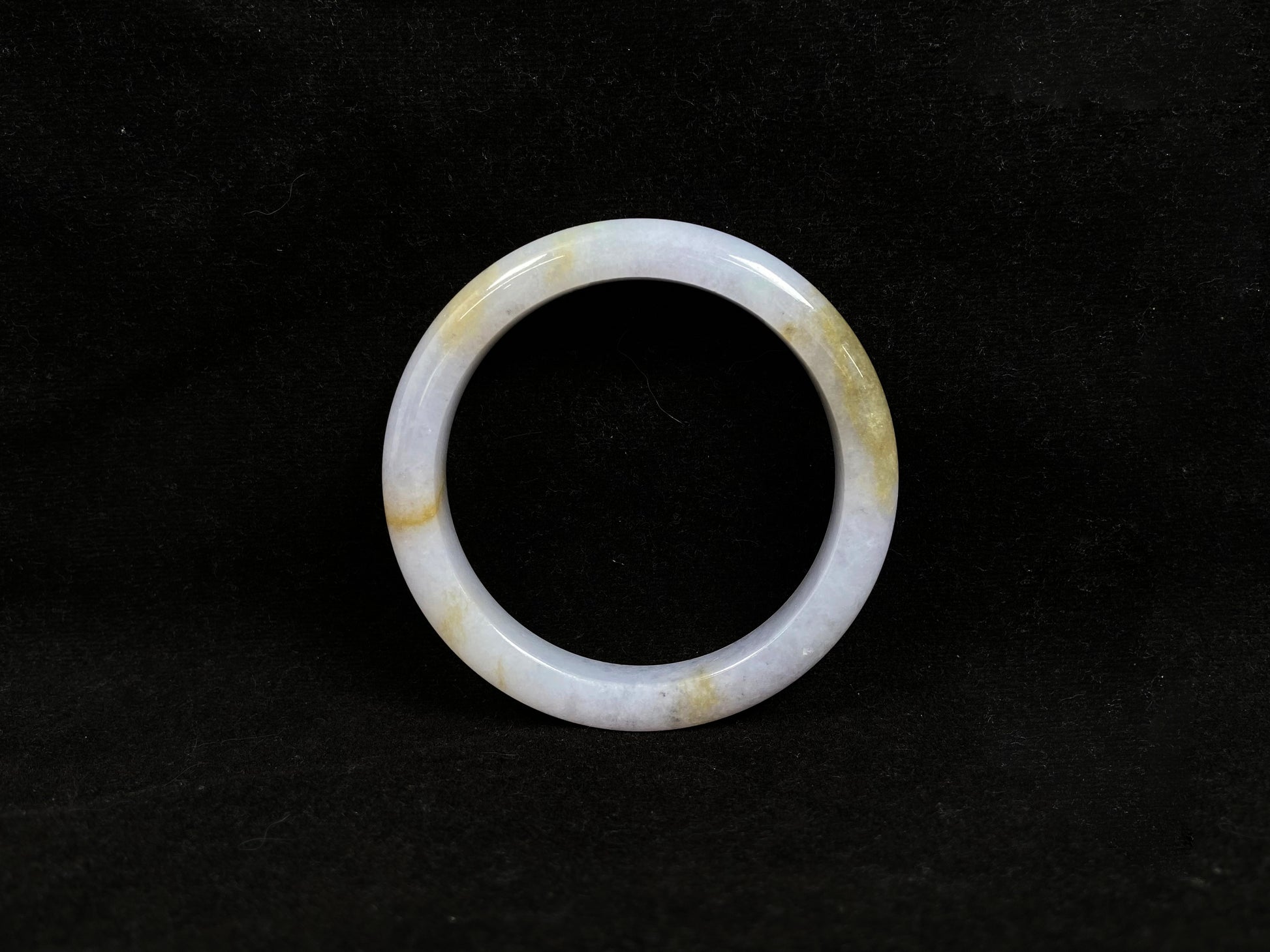 This jadeite bangle features a creamy white base adorned with golden speckles.