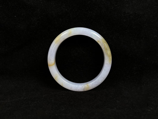 This jadeite bangle features a creamy white base adorned with golden speckles.