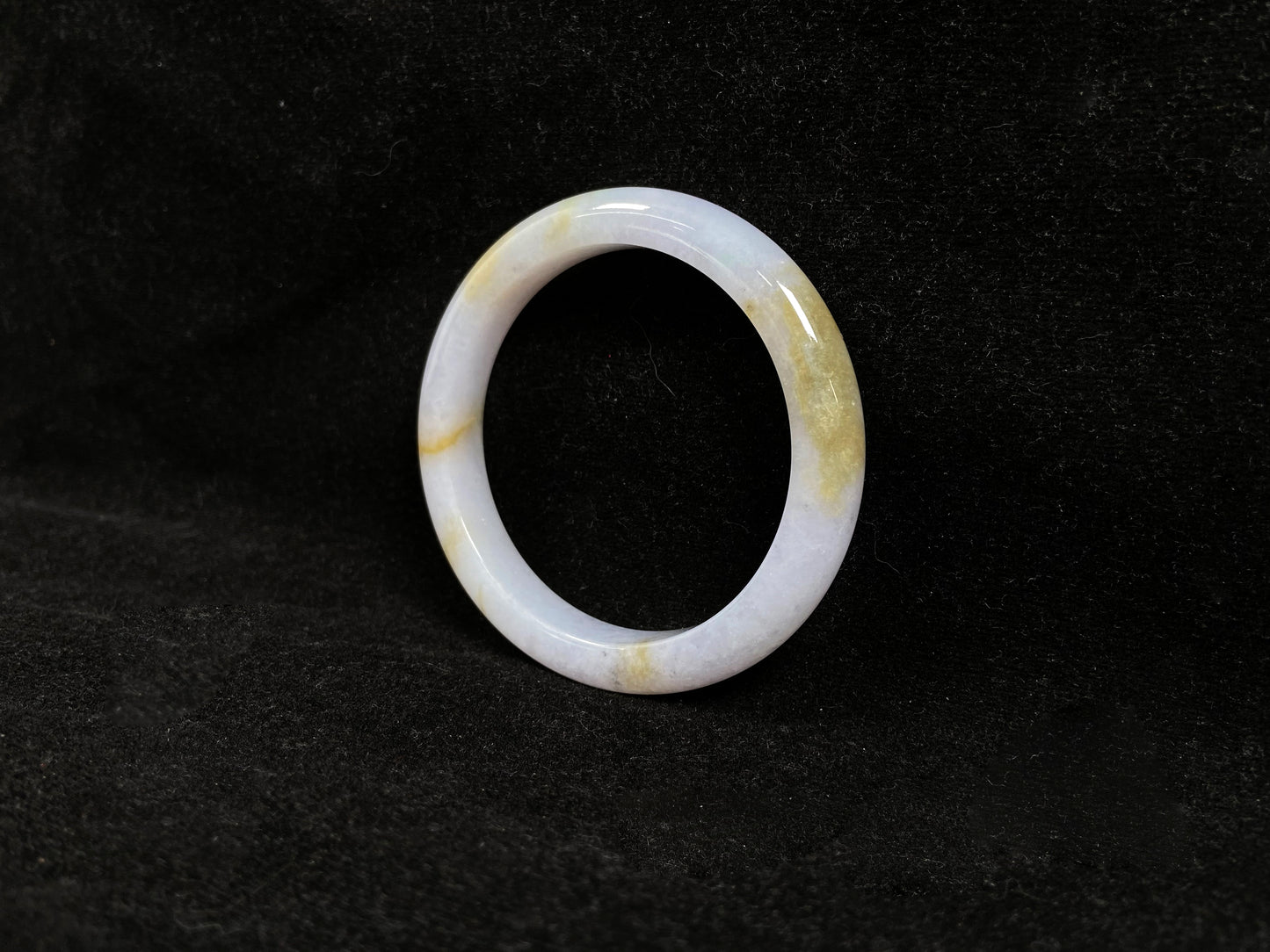 This jadeite bangle features a creamy white base adorned with golden speckles.