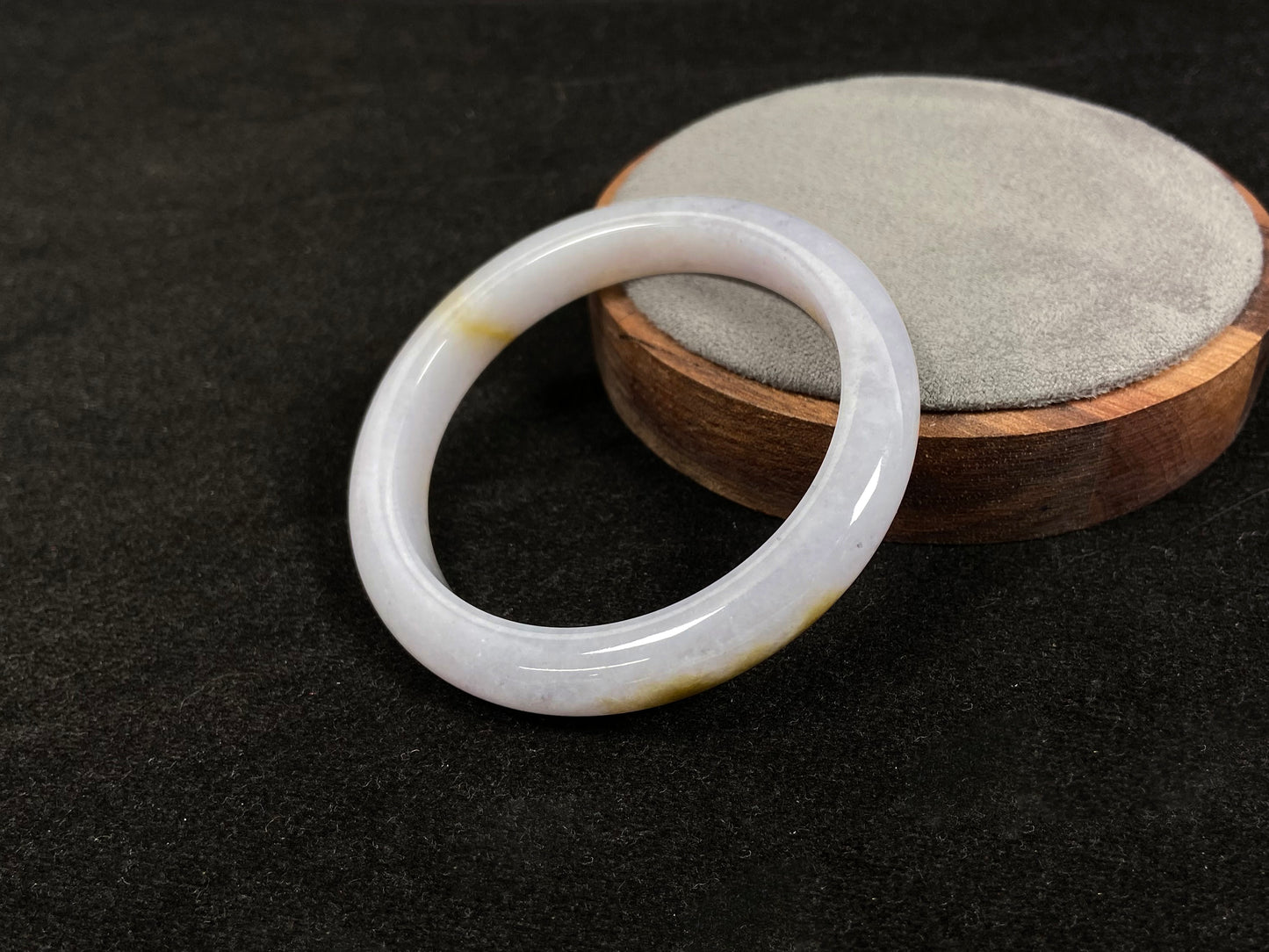 This jadeite bangle features a creamy white base adorned with golden speckles.