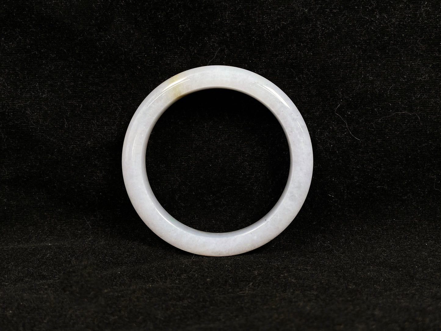 This jadeite bangle features a creamy white base adorned with golden speckles.