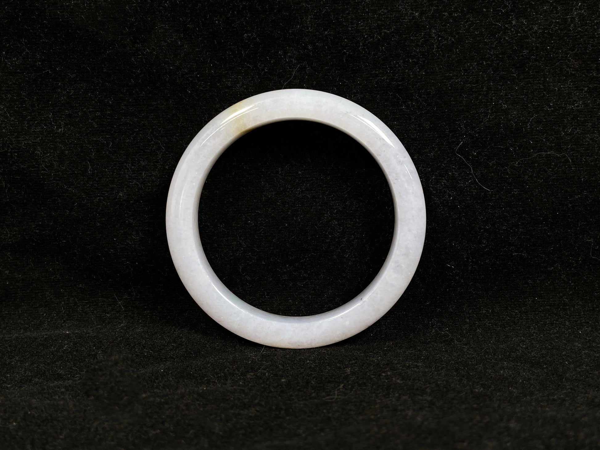 This jadeite bangle features a creamy white base adorned with golden speckles.
