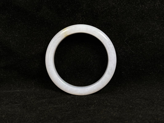 This jadeite bangle features a creamy white base adorned with golden speckles.