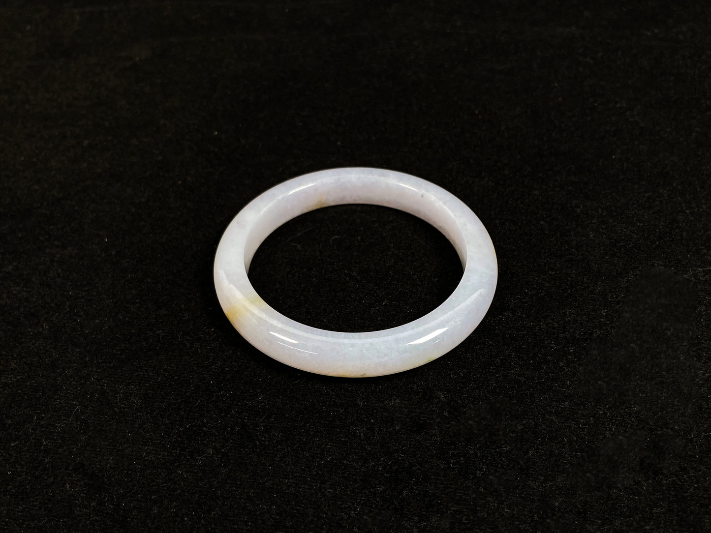 This jadeite bangle features a creamy white base adorned with golden speckles.