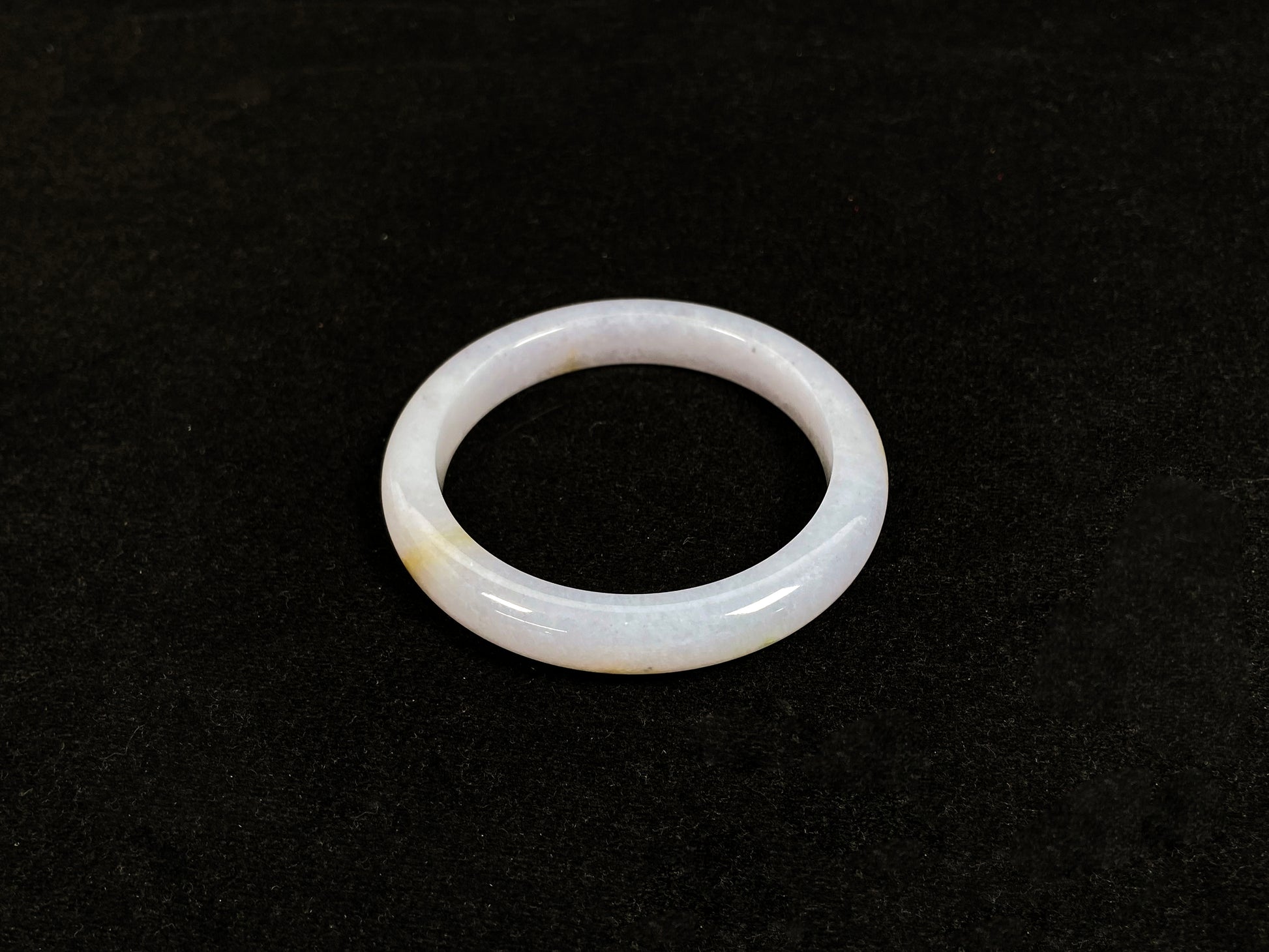 This jadeite bangle features a creamy white base adorned with golden speckles.