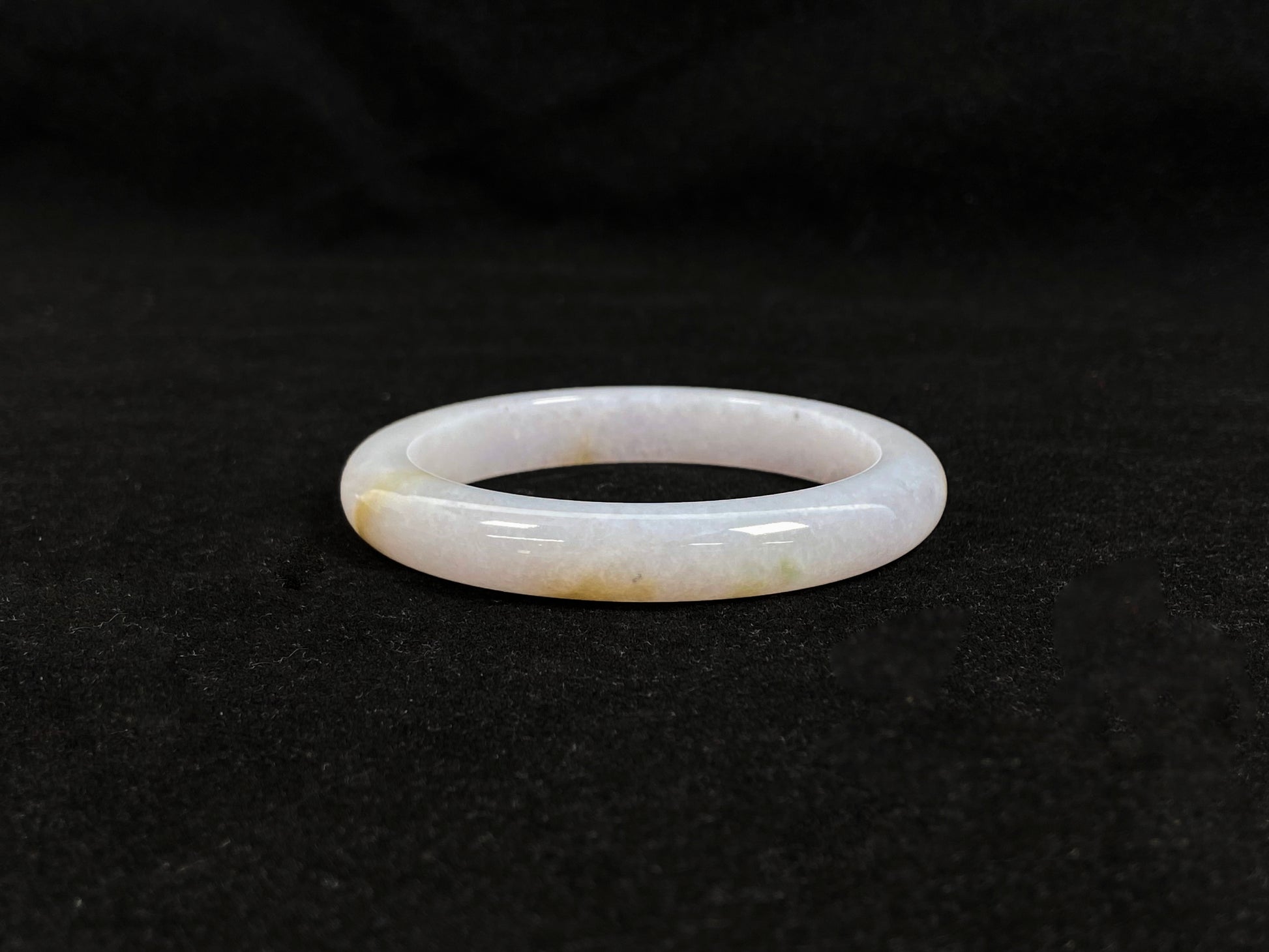 This jadeite bangle features a creamy white base adorned with golden speckles.