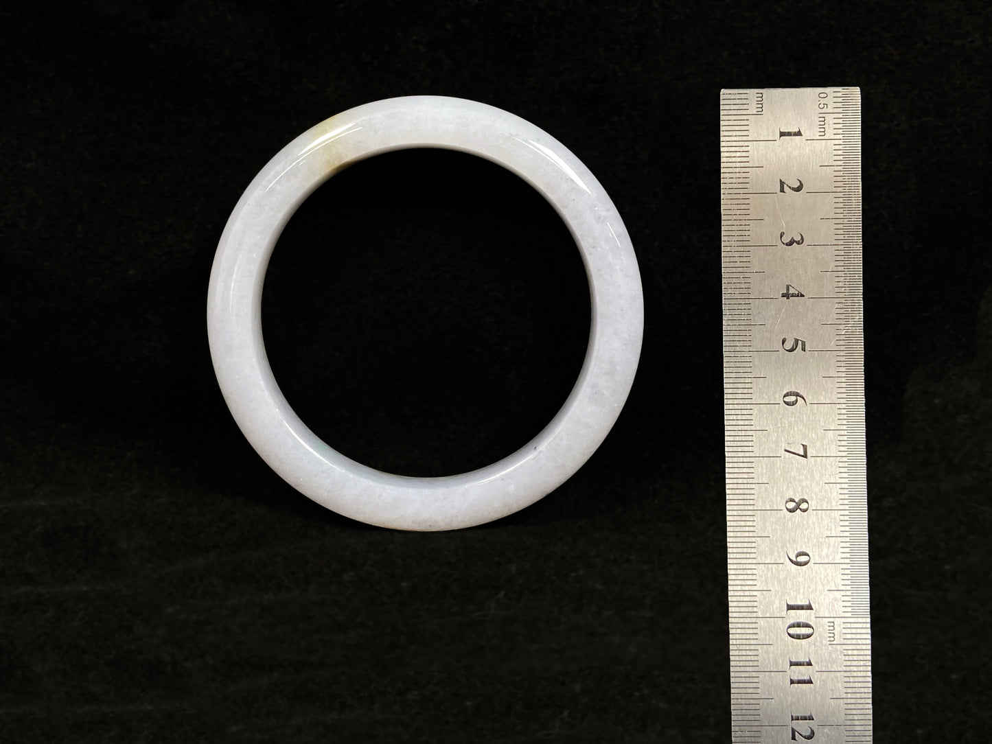 This jadeite bangle features a creamy white base adorned with golden speckles.