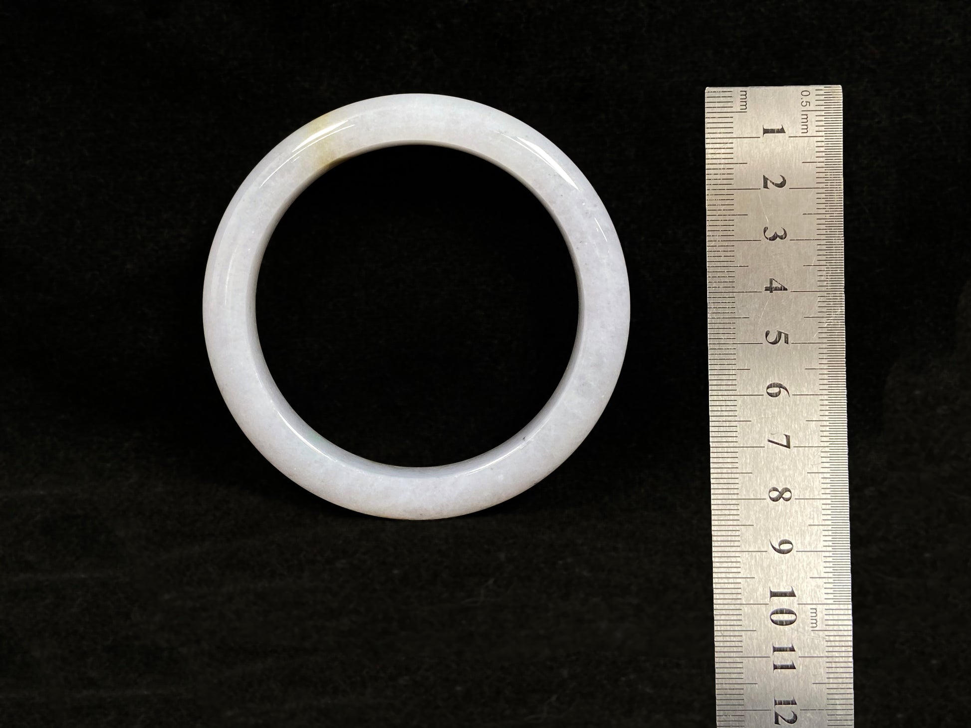 This jadeite bangle features a creamy white base adorned with golden speckles.