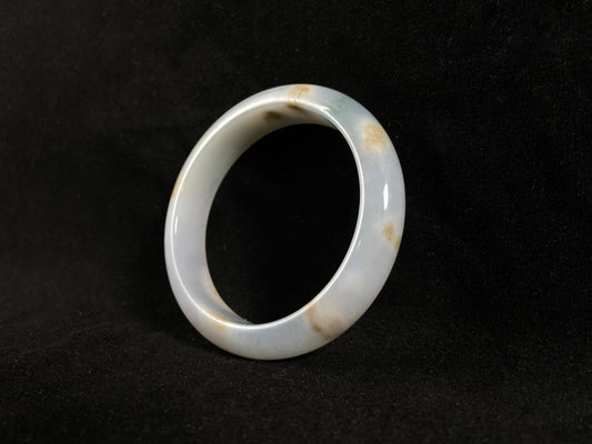 Natural ivory jade bangle with speckled gold and subtle green tones.