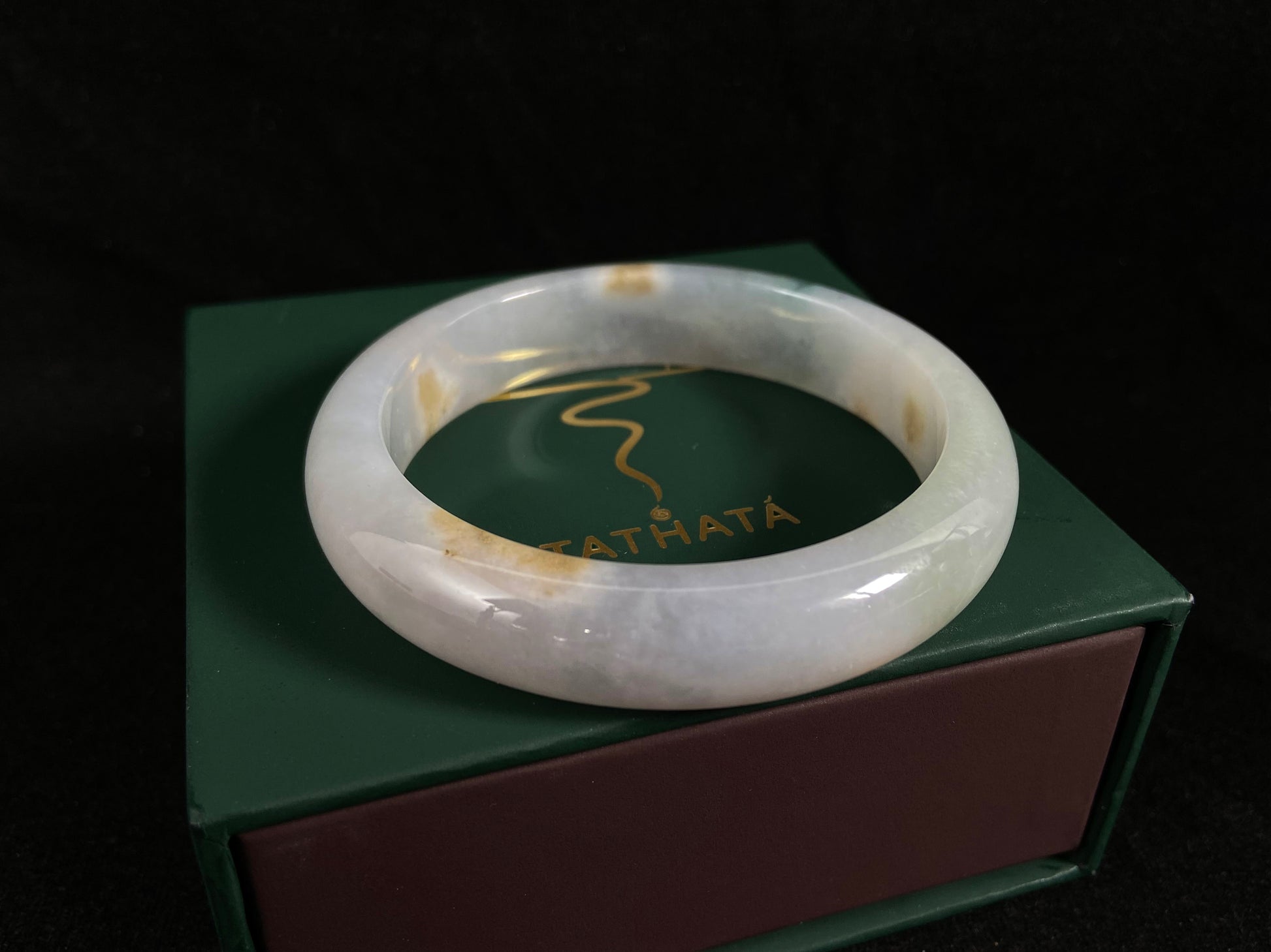 Natural ivory jade bangle with speckled gold and subtle green tones.