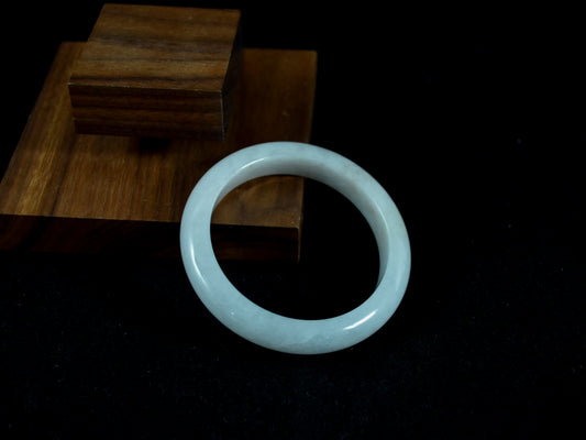 Jade bracelet on a dark surface with wooden blocks in the background