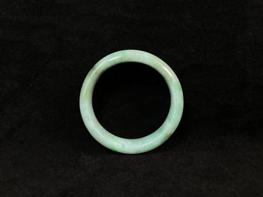 A white-based jade bangle adorned with soft green, deep green and delicate gold speckles.