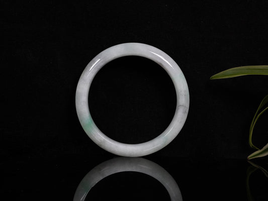 A milky white with pale green speckles jadeite bangle.