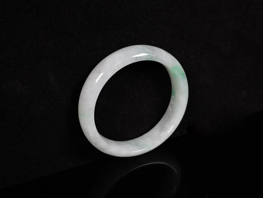 A milky white with pale green speckles jadeite bangle.