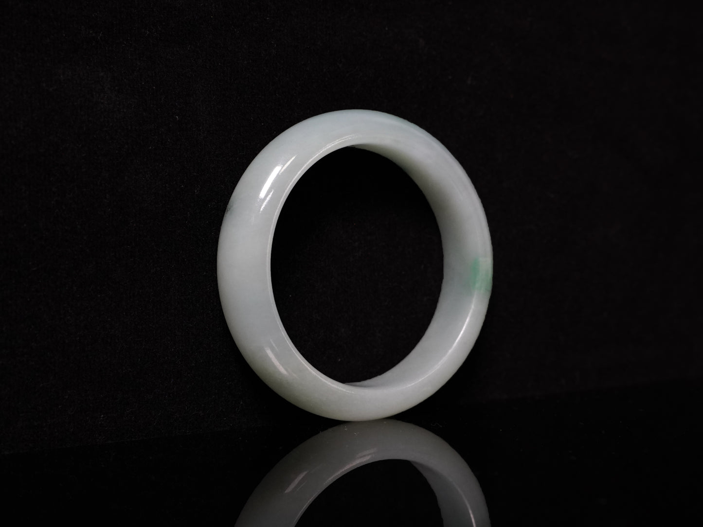 This bangle features a soft, translucent pale white base with a delicate swirl of light emerald green.