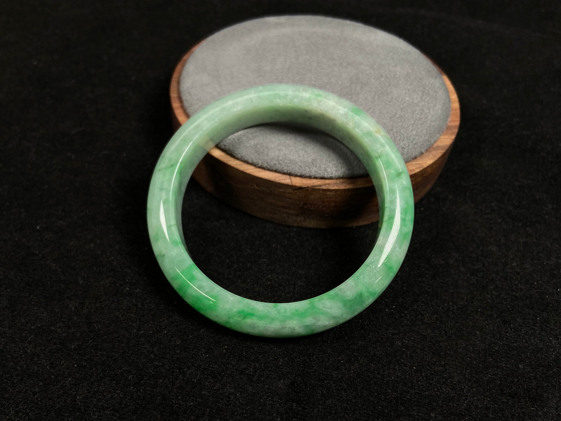 This white-based jade bangle features evenly distributed vibrant green.