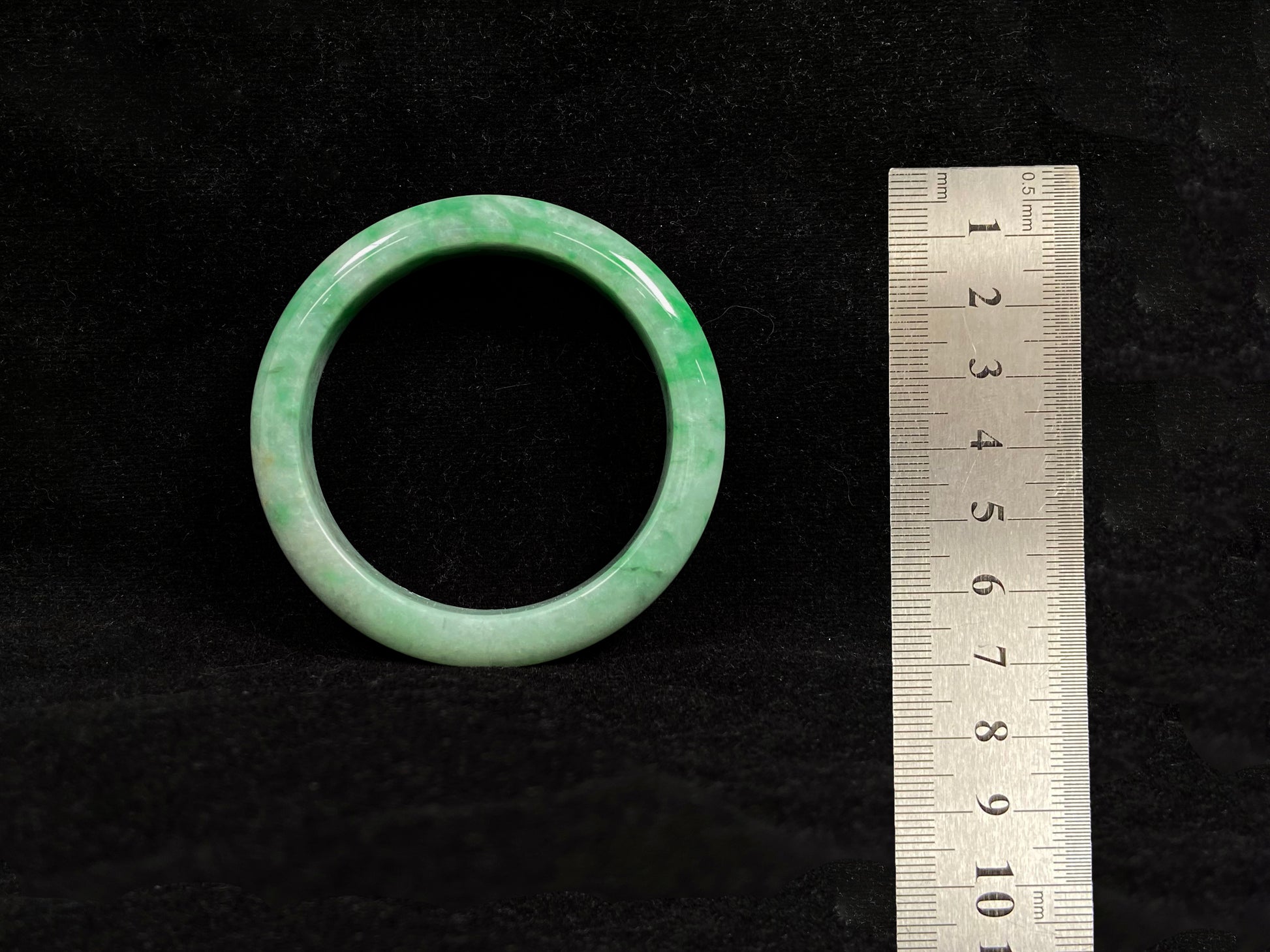 This white-based jade bangle features evenly distributed vibrant green.