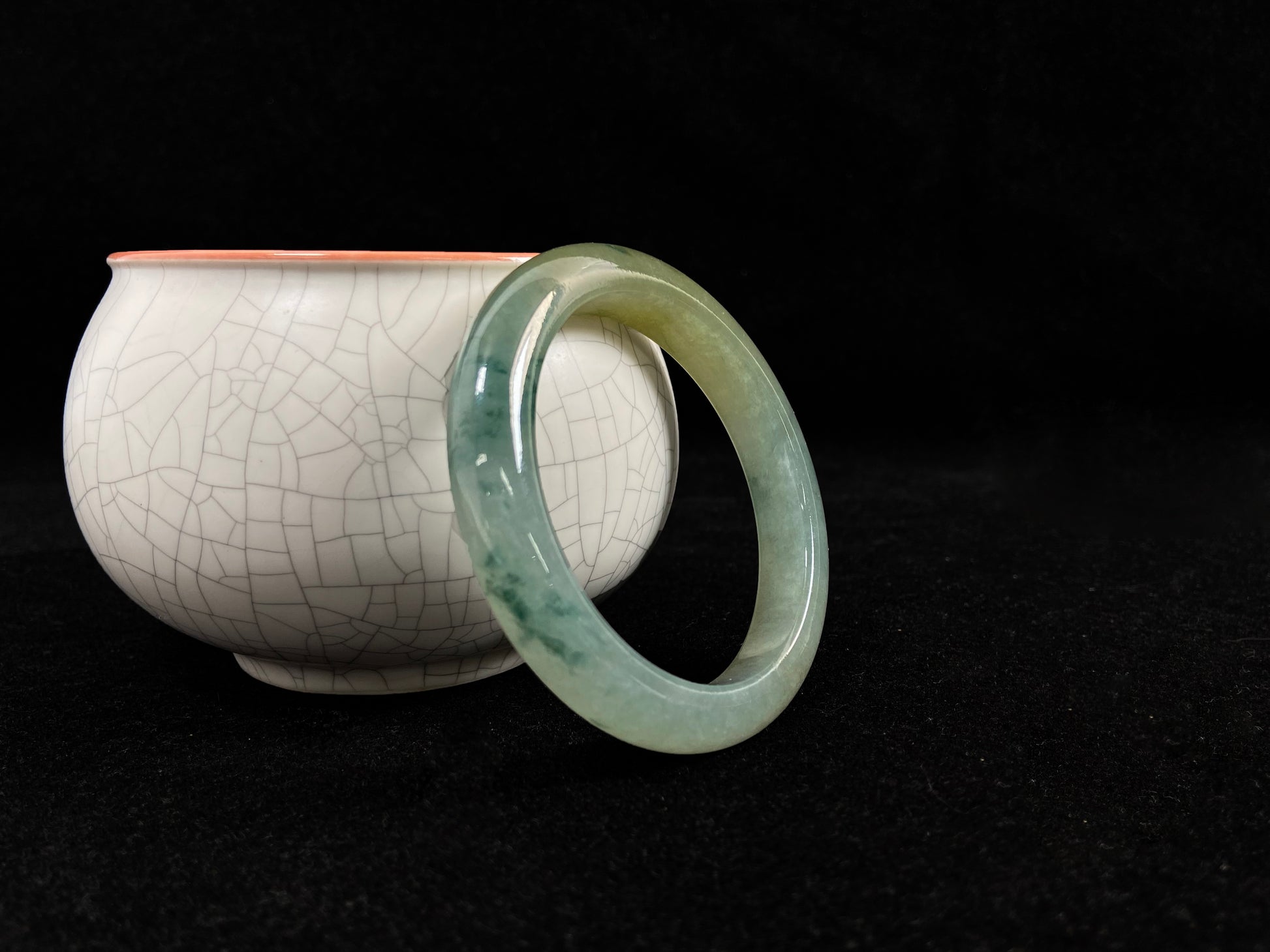 This jadeite bangle features a light green translucent base with floating green patches and integral areas of golden.