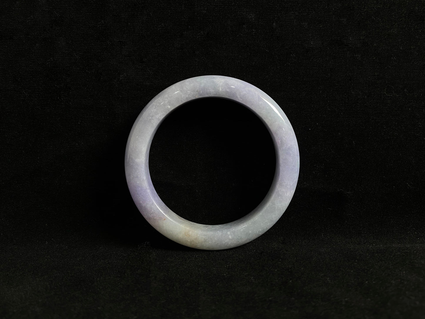 This exquisite jade bangle features a pristine white base adorned with delicate purple accents, creating an elegant color contrast.