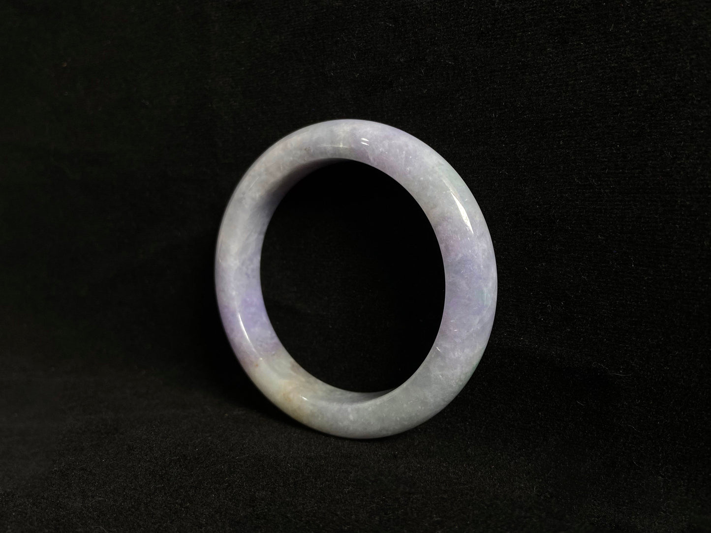 This exquisite jade bangle features a pristine white base adorned with delicate purple accents, creating an elegant color contrast.