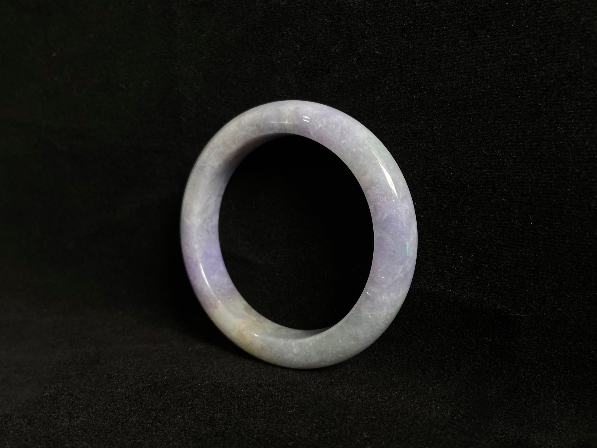This exquisite jade bangle features a pristine white base adorned with delicate purple accents, creating an elegant color contrast.