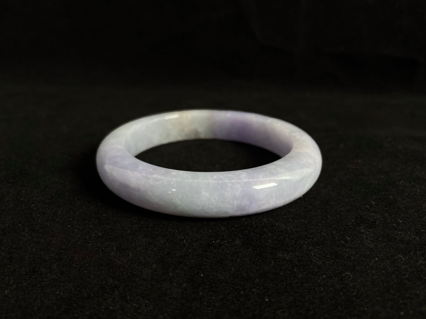 This exquisite jade bangle features a pristine white base adorned with delicate purple accents, creating an elegant color contrast.