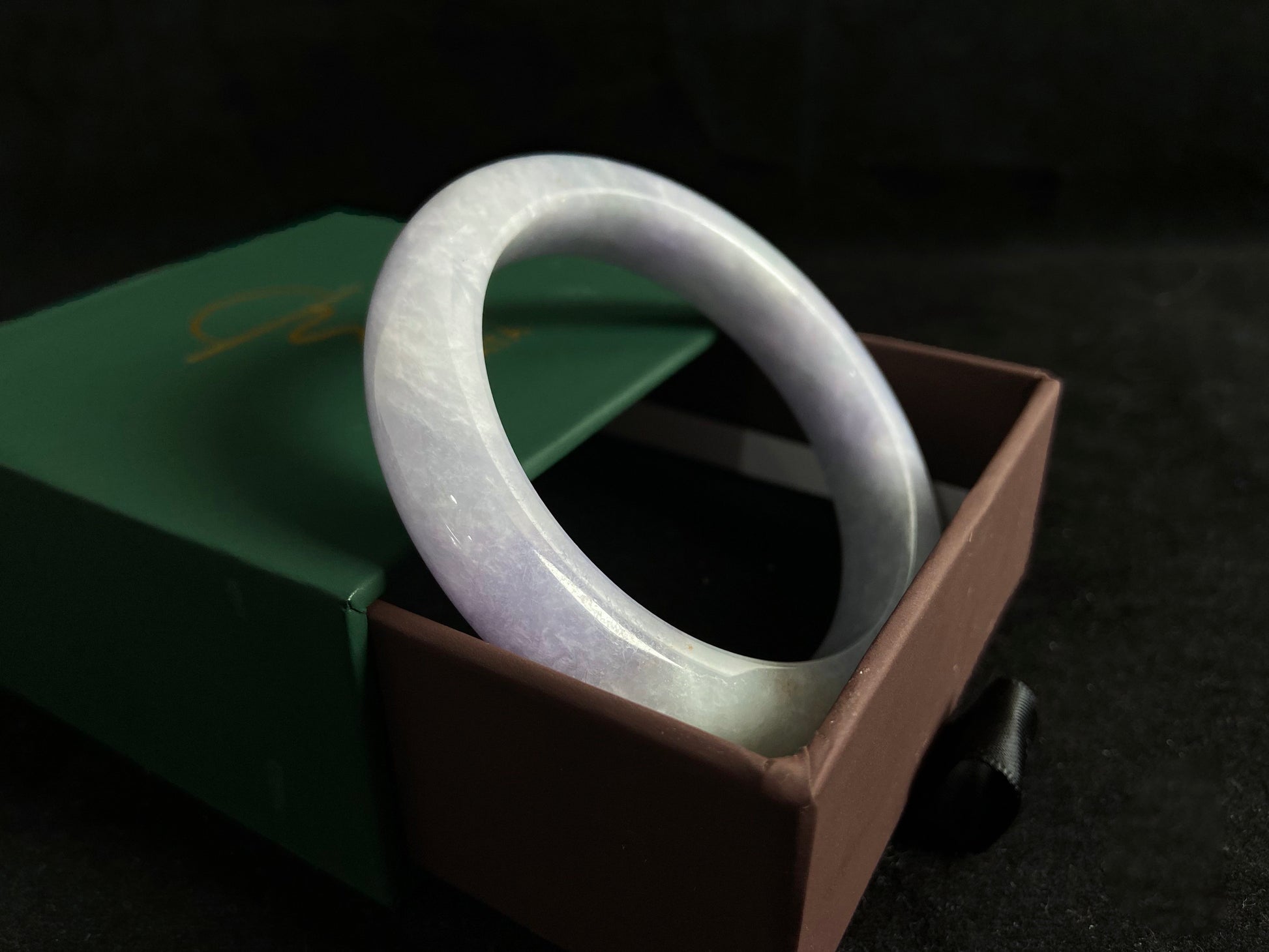 This exquisite jade bangle features a pristine white base adorned with delicate purple accents, creating an elegant color contrast.