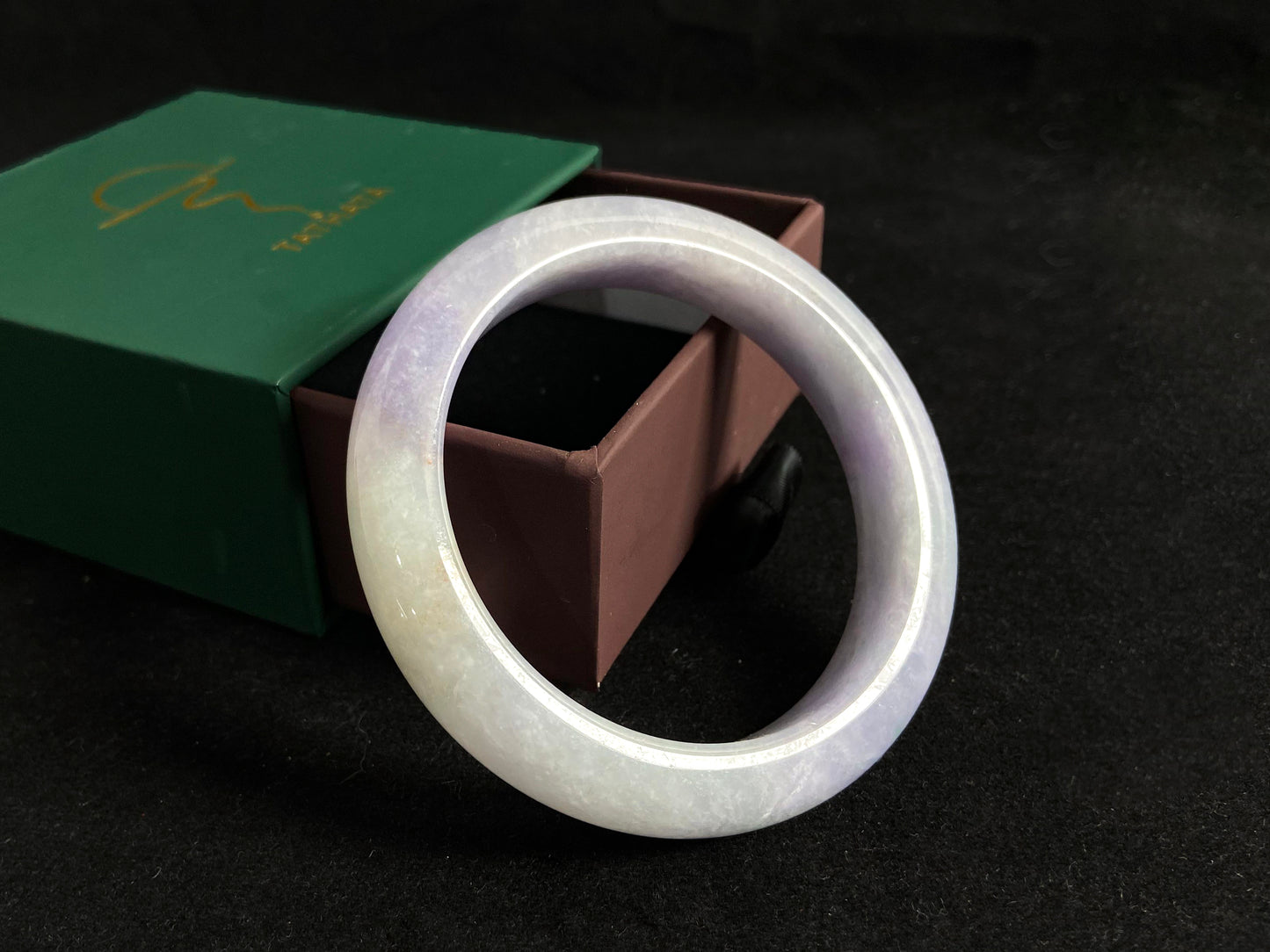 This exquisite jade bangle features a pristine white base adorned with delicate purple accents, creating an elegant color contrast.