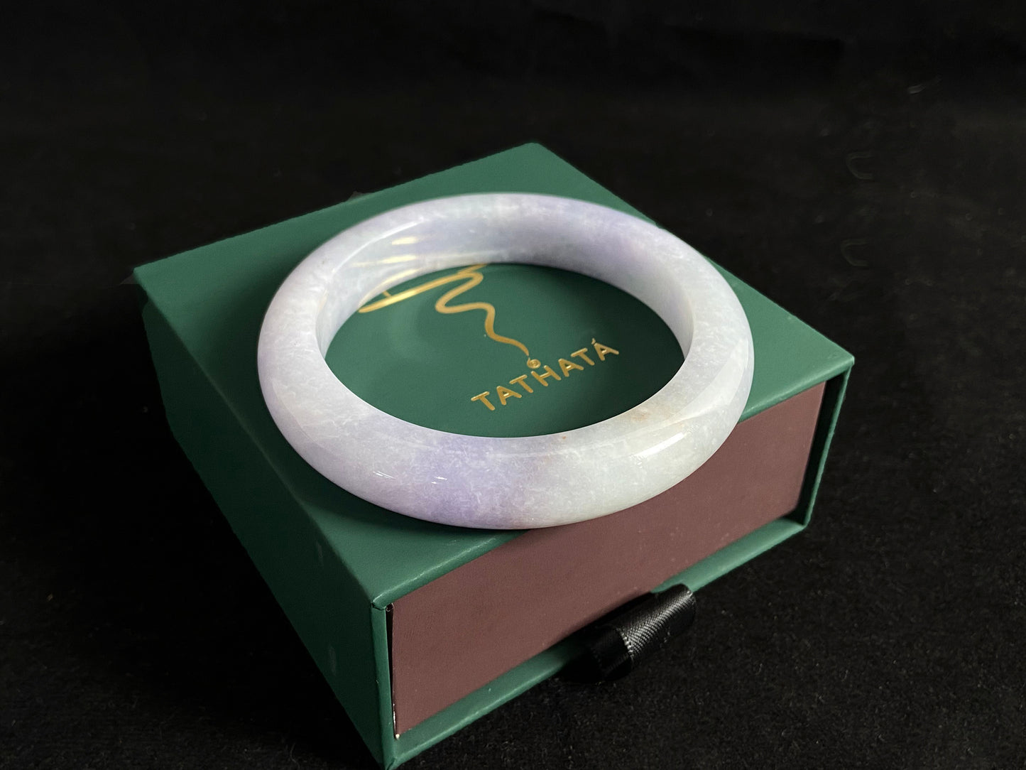 This exquisite jade bangle features a pristine white base adorned with delicate purple accents, creating an elegant color contrast.