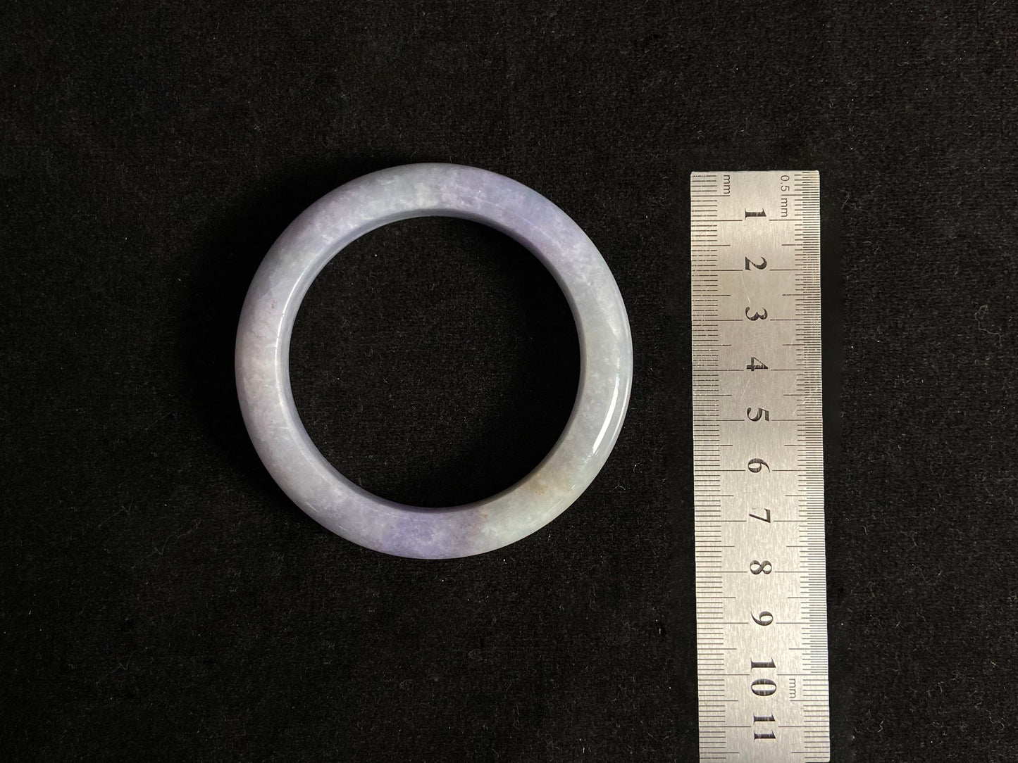 This exquisite jade bangle features a pristine white base adorned with delicate purple accents, creating an elegant color contrast.