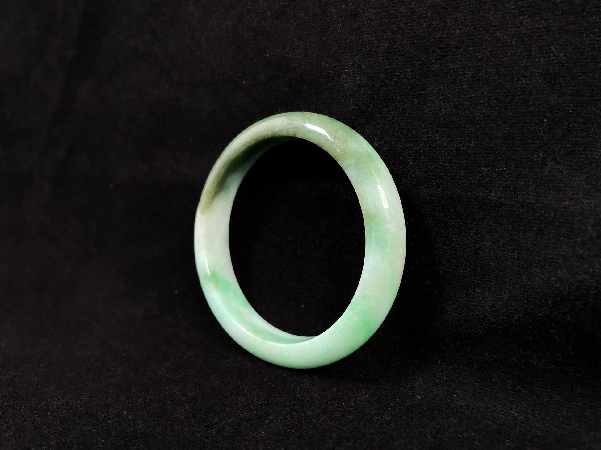 A jade bangle with a milky white base, featuring a large apple green section and a smaller olive green portion.