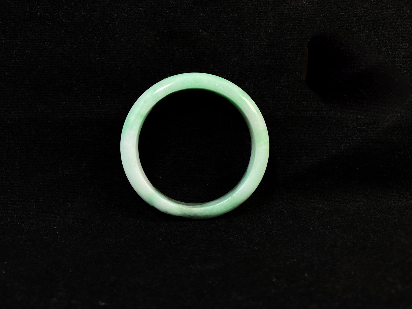 A jade bangle with a milky white base, featuring a large apple green section and a smaller olive green portion.