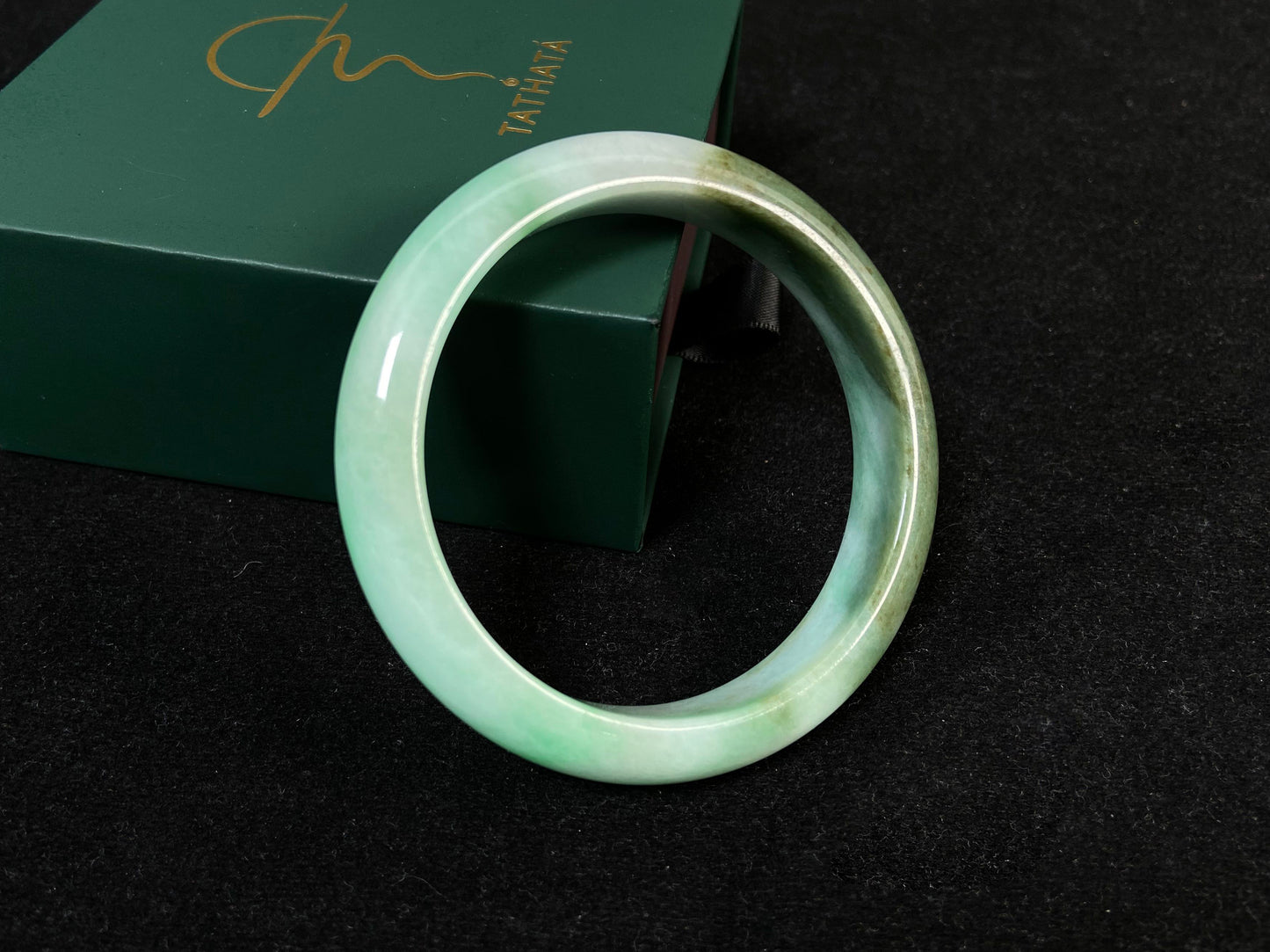 A jade bangle with a milky white base, featuring a large apple green section and a smaller olive green portion.