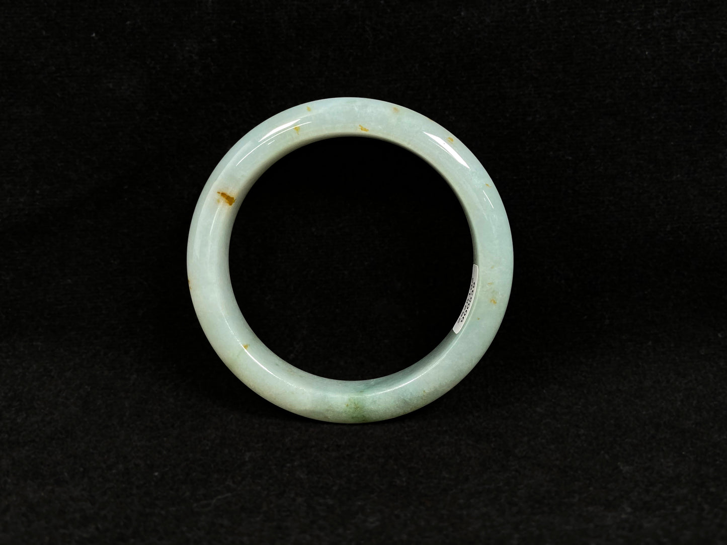 A light green jadeite bangle with gold flecks.