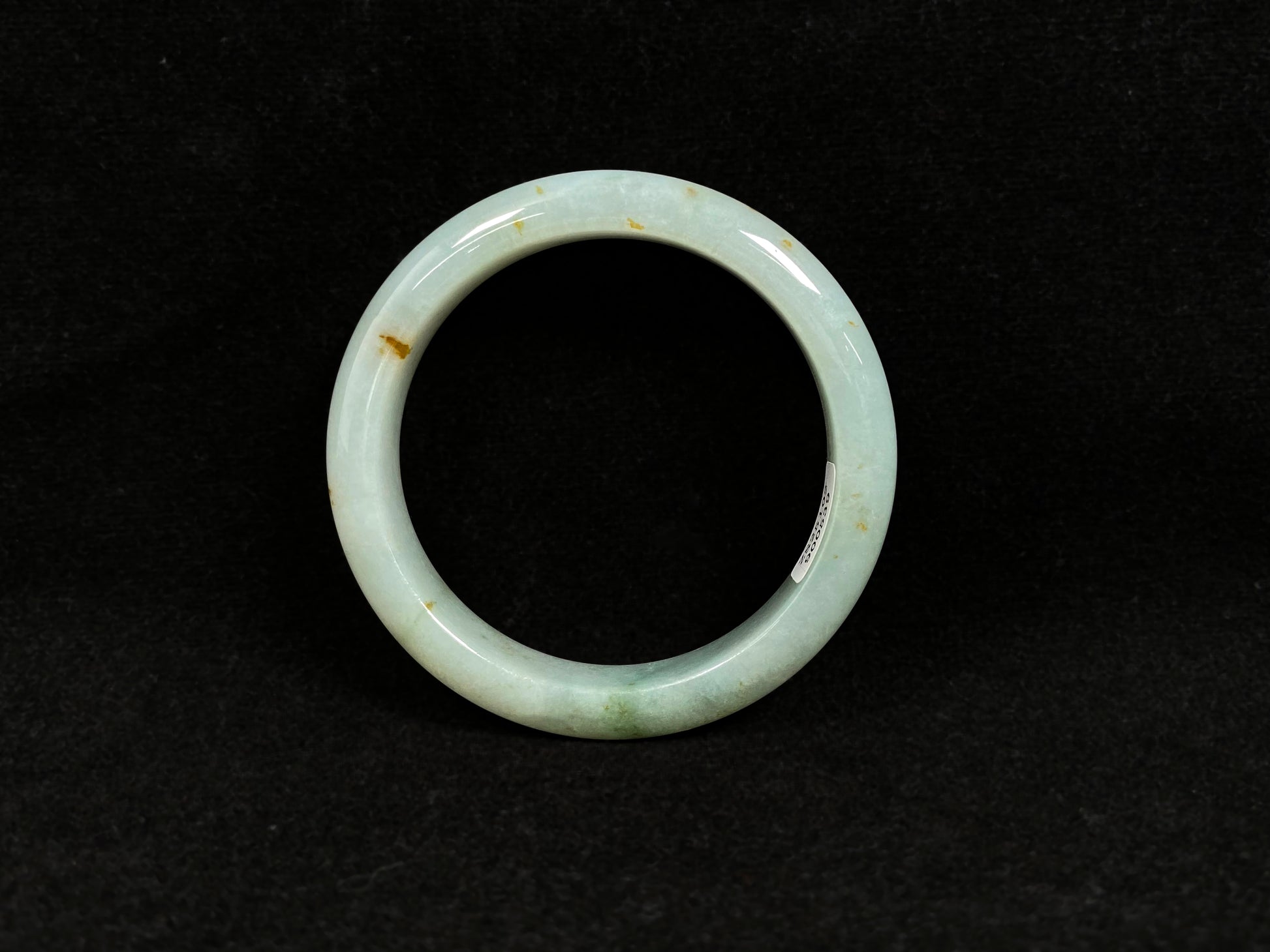 A light green jadeite bangle with gold flecks.