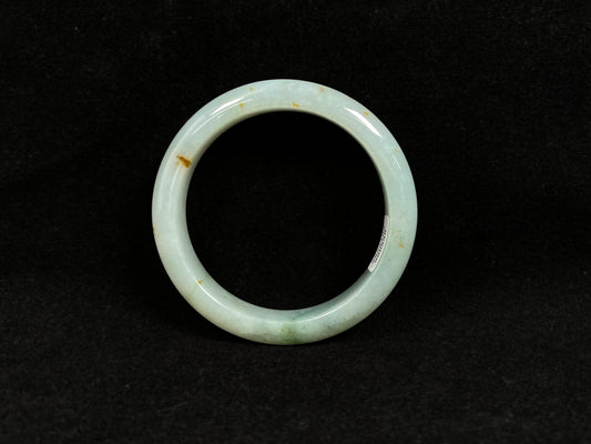 A light green jadeite bangle with gold flecks.