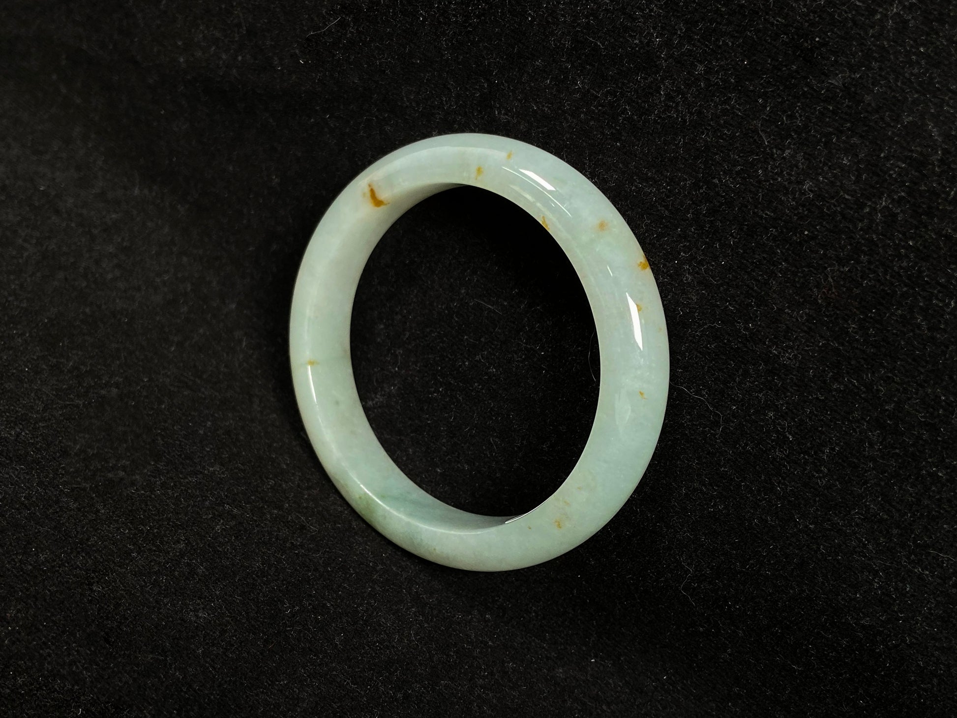 A light green jadeite bangle with gold flecks.